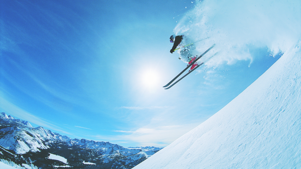 Airborne skier against a blue sky in a cloud of powder