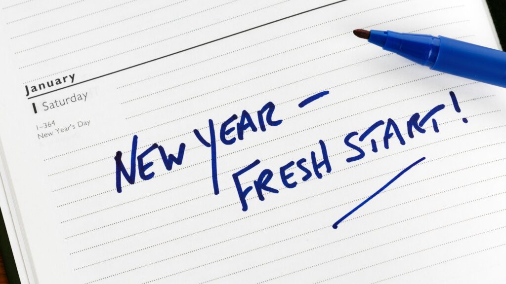 A calendar planner page on January that says in blue marker "New Year – Fresh Start!"